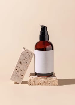 Brown glass one pump bottle near beige stones on light yellow close up, mockup. Skincare beauty product package. Natural cosmetics, minimal composition..