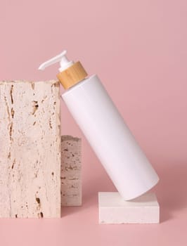 White one pump bottle lies on travertine stone on light pink, close up, mockup. Skincare beauty product. Natural cosmetics, lotion or cleanser. Minimal composition..