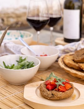 Italian summer appetizer Friselle with cherry tomatoes, oil and rucola served outdoor with glasses of red wine. Tipical Apulian Dried bread, made in Salento. Local cousine. Vegetarian food