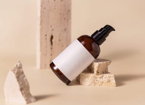 Brown glass one pump bottle near beige stones on light yellow close up, mockup. Skincare beauty product package. Natural cosmetics, minimal composition..