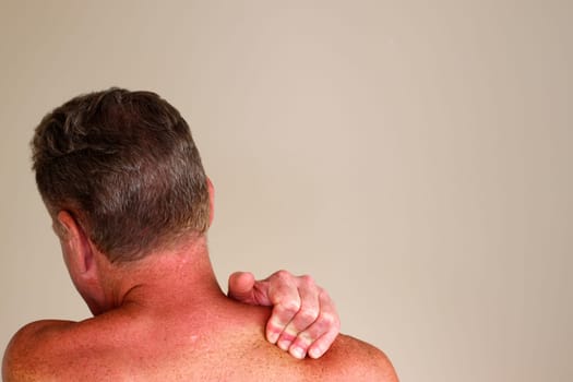 Left fingers and hand of a shirtless mature white male with brown hair massaging his right shoulder to relive muscle tension Mature caucasian male seen massaging his right shoulder with his left hand