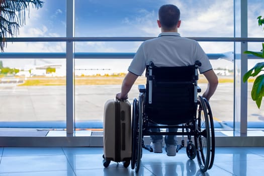 Young man in a wheelchair with luggage at the airport closeup