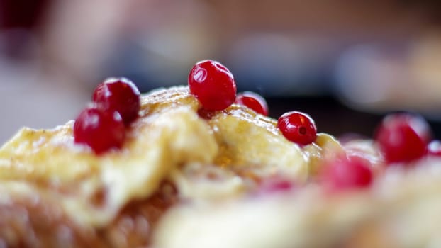Freshly baked croissants with white, soft and sweet cream, red berries on a plate. Continental breakfast of two delicious croissants with cream on a dark wooden table in a restaurant