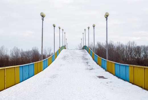 Pedestrian bridge in Chernihiv across the Desna river in the snow on a winter snowy day
