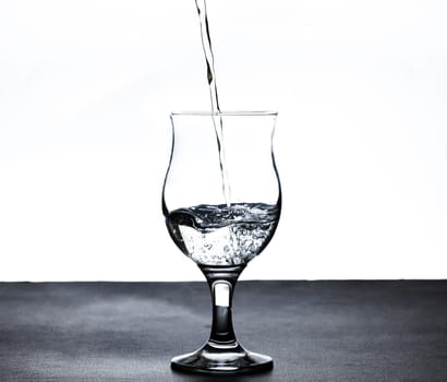 The image of pouring drinking water, into a glass, that makes one feel refreshed on blurred white background