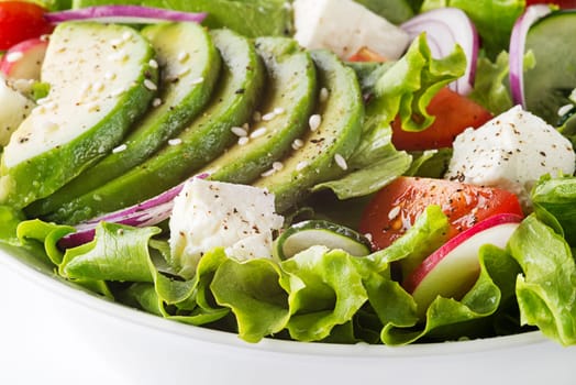 Healthy green salad with avocado feta cheese and fresh vegetables close up
