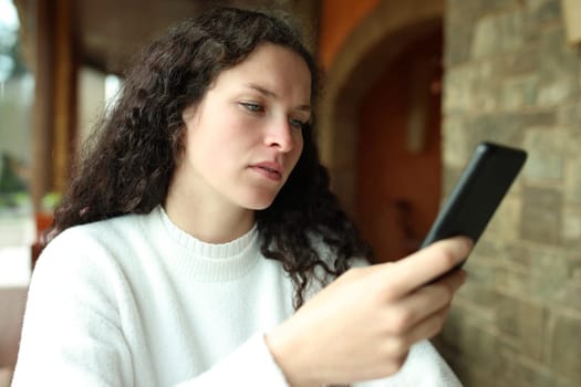 Woman checking smart phone sitting in a restaurant interior