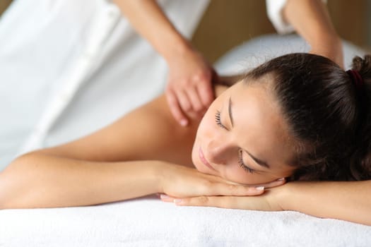 Woman relaxing with closed eyes and therapist massaging her in spa