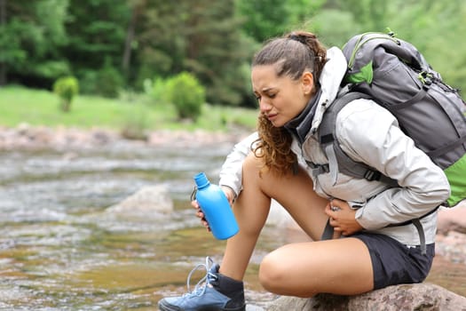 Stressed trekker alone suffering belly ache after drinking river water in the mountain