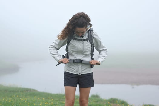 Front view portrait of a hiker adjusting the backpack strap in the mountain