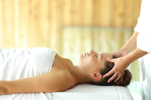 Side view portrait of a woman relaxing receiving a facial massage in spa