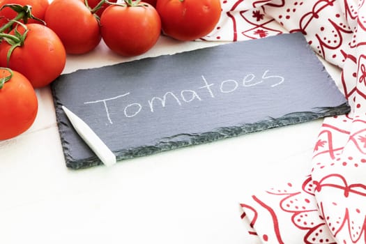 Fresh tomatoes and a chalkboard sign with tomatoes written on it.