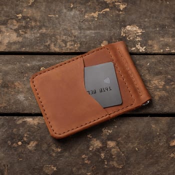 Leather red wallet with credit card on old wooden background. Business and wealth concept.