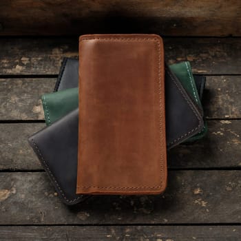 Set of stylish leather wallets on a vintage wooden background. Red, black, brown, green. Place for text
