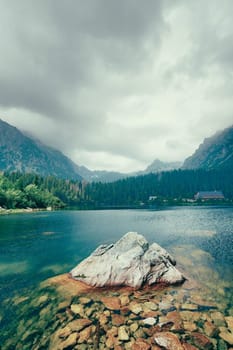 Peaceful mountain lake with big rock in water. Beauty world. Artistic picture.