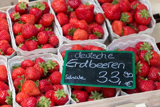 Cups of fresh sweet quality strawberries at marketplace. Local bio fruit sale with german euro price tag at inflation time in germany.