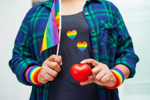 Asian woman holding red hert with rainbow flag, LGBT symbol rights and gender equality, LGBT Pride Month in June.
