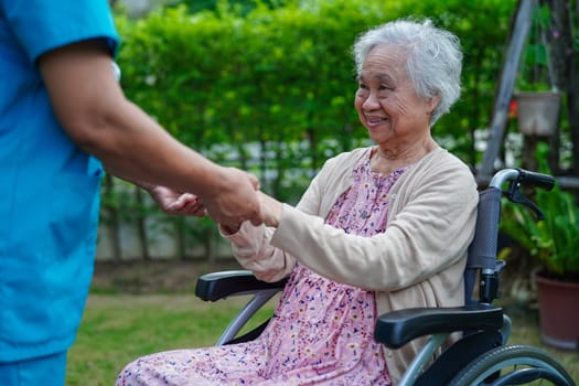 Caregiver help Asian elderly woman disability patient in nursing hospital, medical concept.