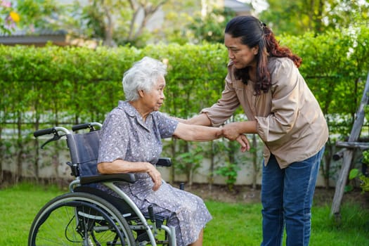 Caregiver help Asian elderly woman disability patient sitting on wheelchair in park, medical concept.