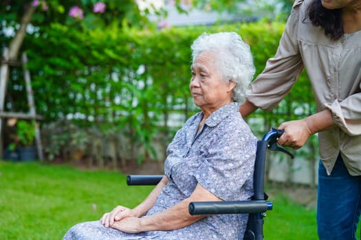 Caregiver help Asian elderly woman disability patient sitting on wheelchair in park, medical concept.
