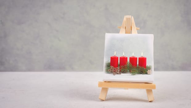Advent wreath, christmas decoration with red candle light, drawing on an easel, copy space for text, holiday greeting card