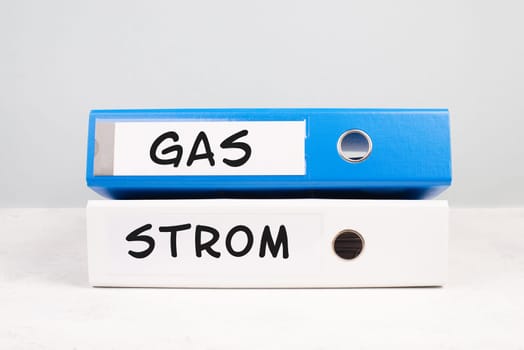 The words gas and electricity are standing in german language on the folders, increasing prices, high living expenses, financial crisis, inflation