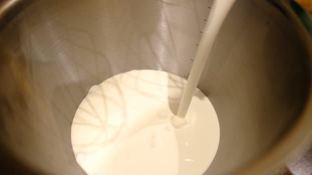Whipping cream whites in food processor. Hands of professional male chef adding cream to the bowl of modern silver kitchen stand mixer.
