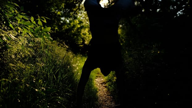 man walks on hands in the forest at sunset, sunrise