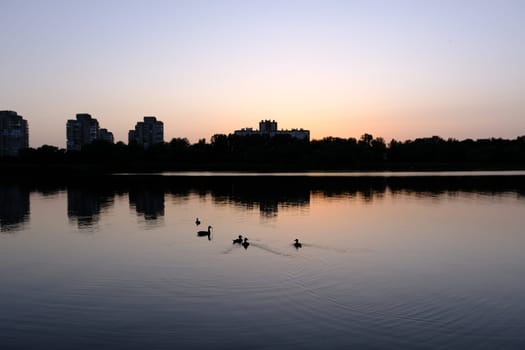 Sumy City midtown silhouette panorama at sunset with skyscrapers and colorful sky over the river.
