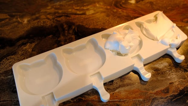 Making homemade popsicles. man pouring ice cream in freezer molds.