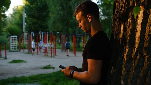 Young man showing sincere excitement about his favorite team victory. Guy being happy winning a bet in online sport gambling application on his mobile phone. Focus is on hand.