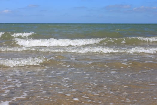 Waves with whitecaps flood the sandy beach.Wellen mit weißen Schaumkronen überfluten den Sandstrand .