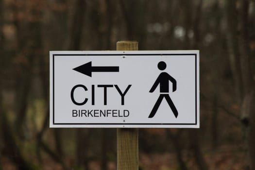 A signboard with inscription, arrow and symbol.Ein Hinweisschild mit Aufschrift, Pfeil und Symbol.