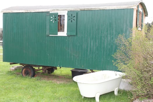 A green construction trailer, with a white bathtub in the foreground.ein grüner Bauwagen, mit einer weißen Badewanne im Vordergrund.