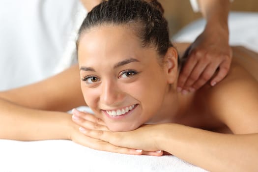 Happy woman looking at you receiving massage by therapist