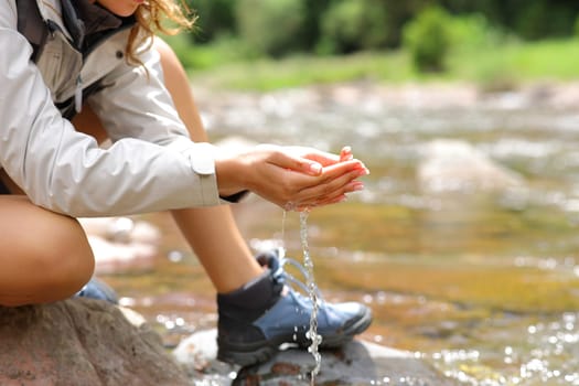 Close up of a trekker with cupped hands catching water from river in the mountain