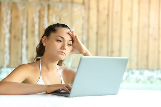 Worried woman unable to relax using laptop in spa