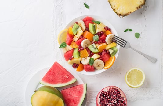 Bowl of healthy fresh fruit salad on white background, top view