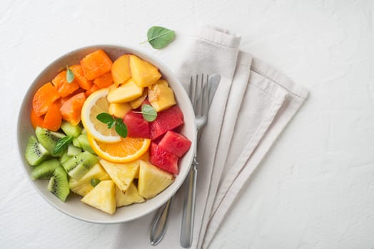 Bowl of healthy fresh tropical fruit salad on white background. Top view.