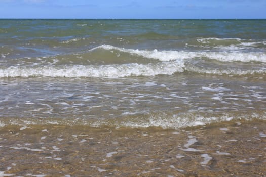 Waves with whitecaps flood the sandy beach.Wellen mit weißen Schaumkronen überfluten den Sandstrand .