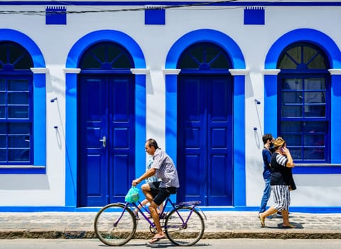 Morretes, Brazil, January 21, 2022: people are passing by a colorful house facade in historic town of Morretes, Brazil