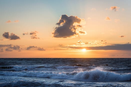 colored sunset with cloud cover over the sunset at the beach - dramatic sunset on the baltic sea