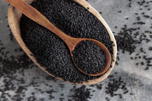 Indian spice Black cumin (nigella sativa or kalonji) seeds in bowl with spoon on grey table top view. Traditional medicine, healthy and vegetarian food concept.