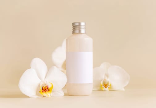 Cosmetic bottle with blank label near white orchid flowers on light yellow, close up, mockup. Skincare beauty product, cramor lotion. Exotic natural cosmetics. Minimal composition..