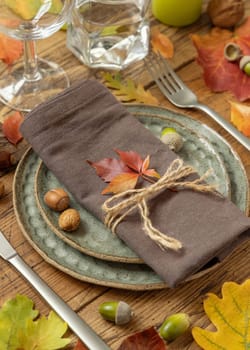 Autumn rustic table setting between leaves and berries on vintage wooden table close up. Thanksgiving, halloween or harvest concept
