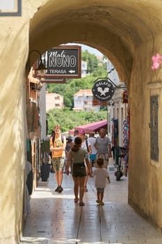 Tourists in an alley with stores in the old town of Krk in Croatia