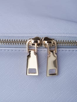 golden zippers with golden zippers are fastened on a blue leather object close-up. High quality photo