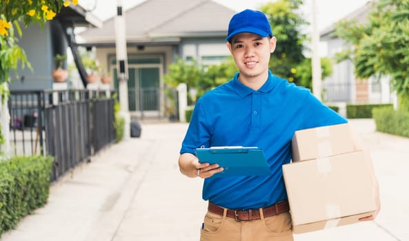 Asian young delivery man courier in uniform hold parcel post boxes service shipment and walking finding and looking for customer home location, Online shopping service concepts