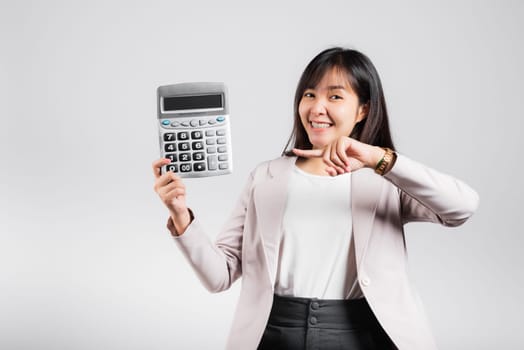 Tax day concept. Woman confident smiling holding calculator and finger point device, Portrait excited happy Asian female studio shot isolated on white background, Account and finance counting income