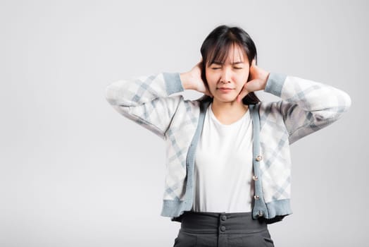 Woman bad mood pain her closed ears with hand palms and close eyes, Asian beautiful young female covers ears for loud noise, studio shot isolated on white background with copy space